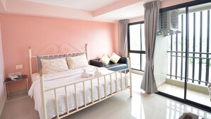 A bedroom with a bed, a nightstand, a window with curtains, and an air conditioning unit. - Kwanchanok Ville (Hua Hin)
