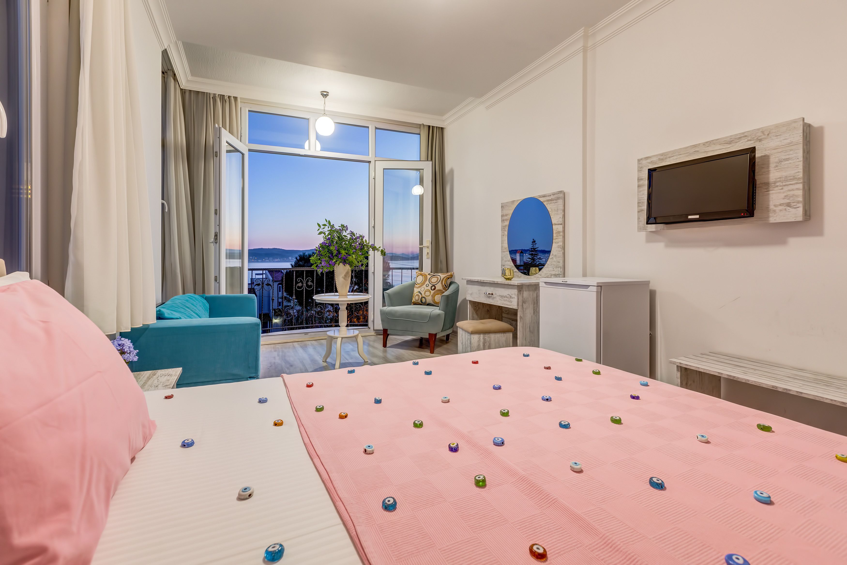 Une chambre d’hôtel avec un lit, un bureau, une chaise, une télévision et un balcon avec vue.