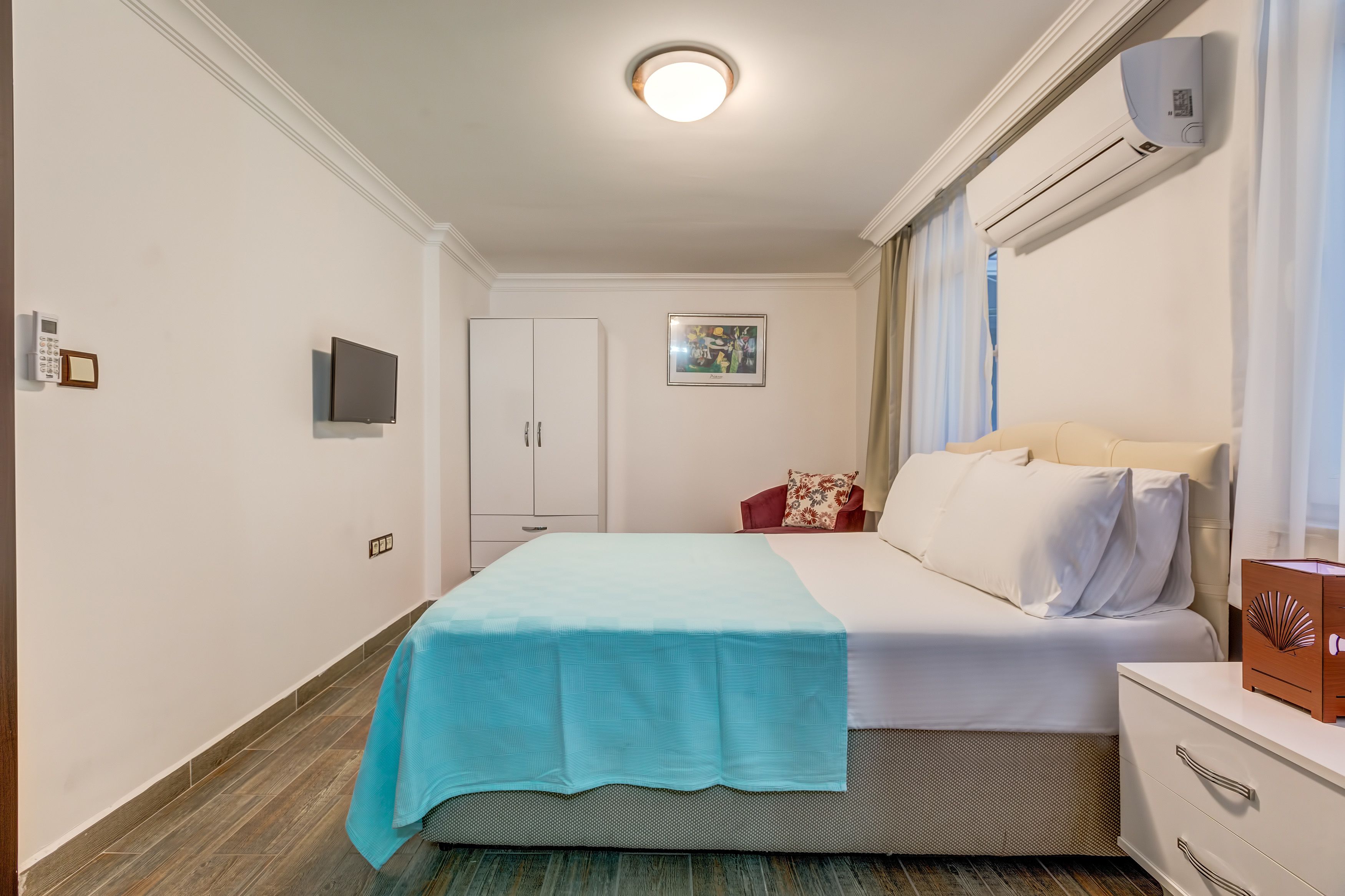 Une chambre d’hôtel comprenant un lit, une table de chevet, une armoire et un appareil de climatisation.