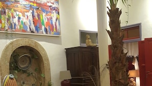 Un accogliente soggiorno con camino, divani in pelle, un tavolino da caffè e diversi oggetti decorativi, tra cui una statua di Buddha, un quadro colorato e una palma alta.
