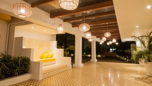 A modern interior with hanging wicker lamps, a white bench with yellow cushions, and a patterned floor.