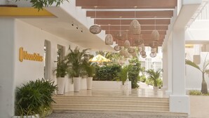 A hotel entrance with a sign reading "Bloom Suites," potted plants, and hanging wicker lamps.