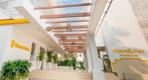 A hotel entrance with a modern design, featuring a staircase, potted plants, and hanging wicker lamps. - BloomSuites - Calangute (Calangute)