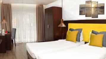 Habitación de hotel con cama, escritorio, silla, televisor y ventana con cortinas.