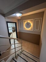 Interior de hotel con una escalera, un letrero en la pared y una vista parcial de la cocina.