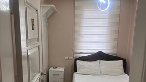 Una camera da letto con un letto, un comodino, una cassettiera, una ventola a soffitto e una finestra con persiane.