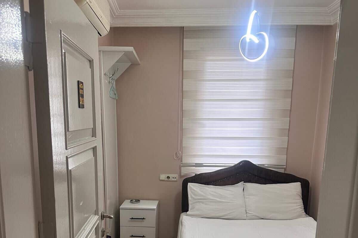 Un dormitorio con cama, mesita de noche, cómoda, ventilador de techo y ventana con persianas.