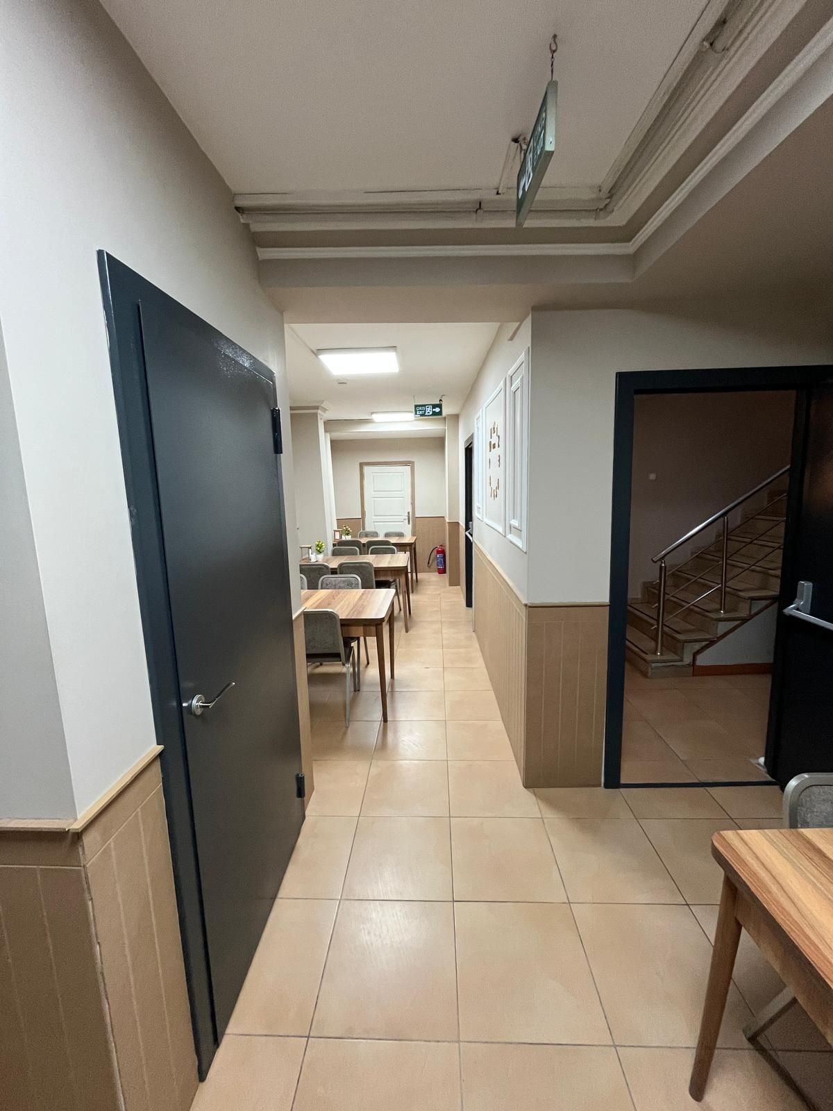 A hotel corridor with a dining area, a staircase, and a door.