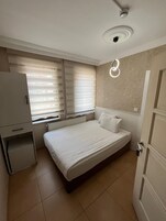 Un dormitorio con cama, radiador, armario y ventana con persianas.