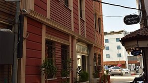 Una stretta strada acciottolata fiancheggiata da edifici rossi, una moto parcheggiata e qualche pianta in vaso.