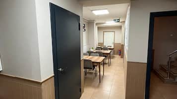 Un pasillo de hotel con una zona de comedor, una escalera y una puerta.
