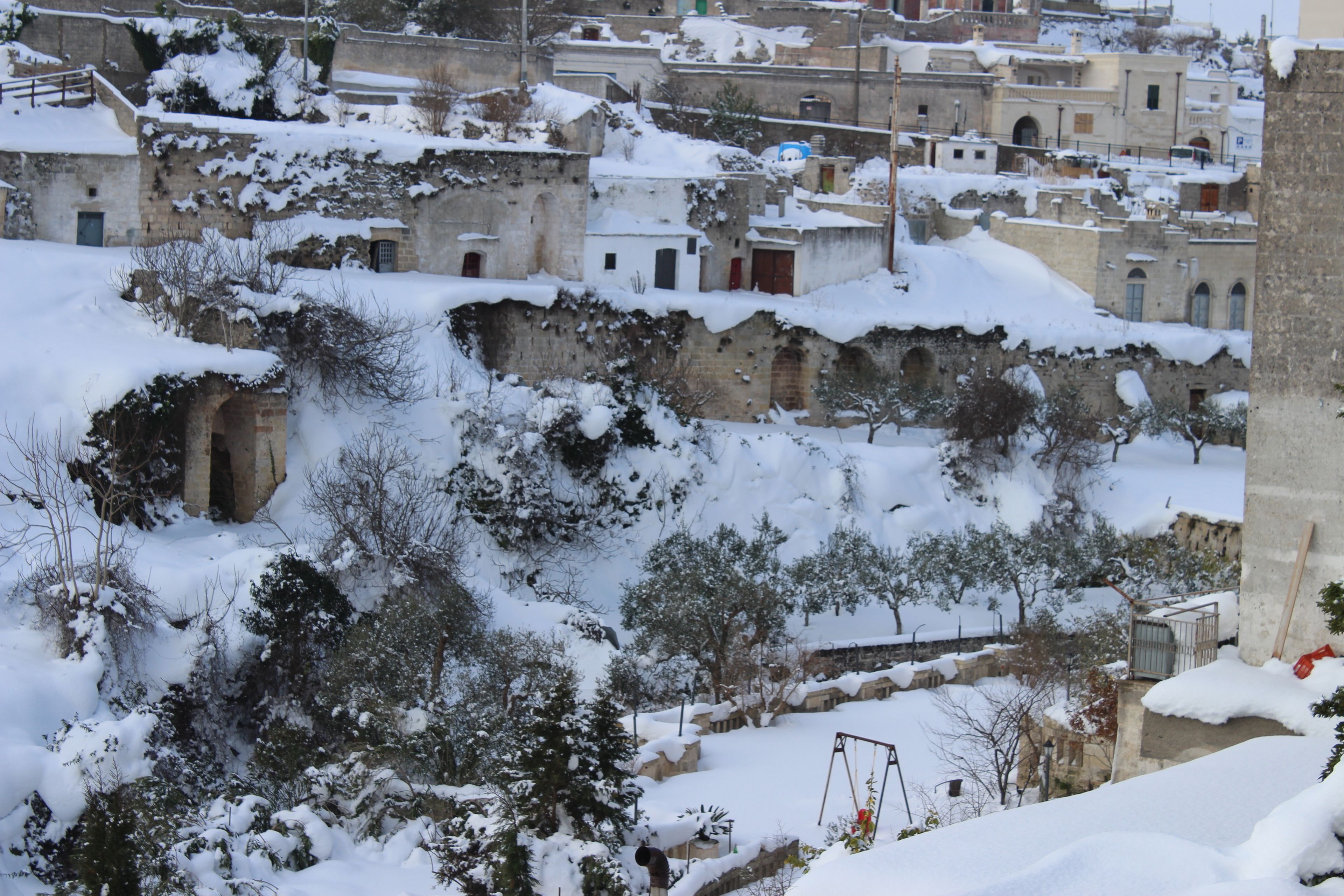 A snow-covered urban landscape with historic buildings and trees.