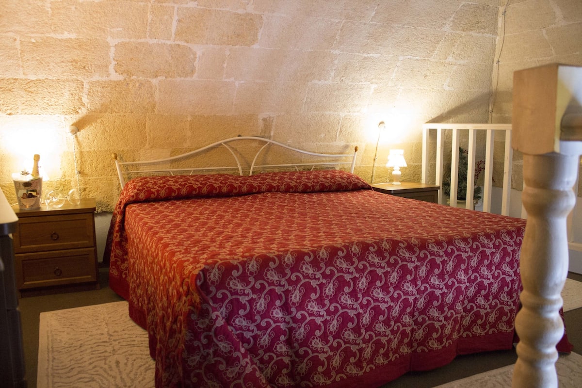 Quarto com cama, mesas de cabeceira e berço.