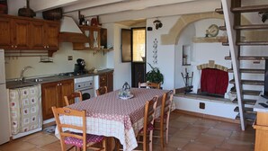 A kitchen with wooden cabinets, a dining table with chairs, a stove, and a sink. - La Ferula Casa Vacanze (Laterza)
