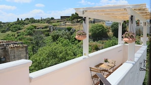 A balcony with a table and chairs, overlooking a lush landscape with trees and buildings. - La Ferula Casa Vacanze (Laterza)