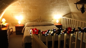 A cozy bedroom with a white crib, a bed with a red bow, and a brick wall. - La Ferula Casa Vacanze (Laterza)