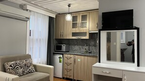 A compact living space with a kitchenette, a sofa, and a flat-screen TV. - Jasmine Apartment (Istanbul)