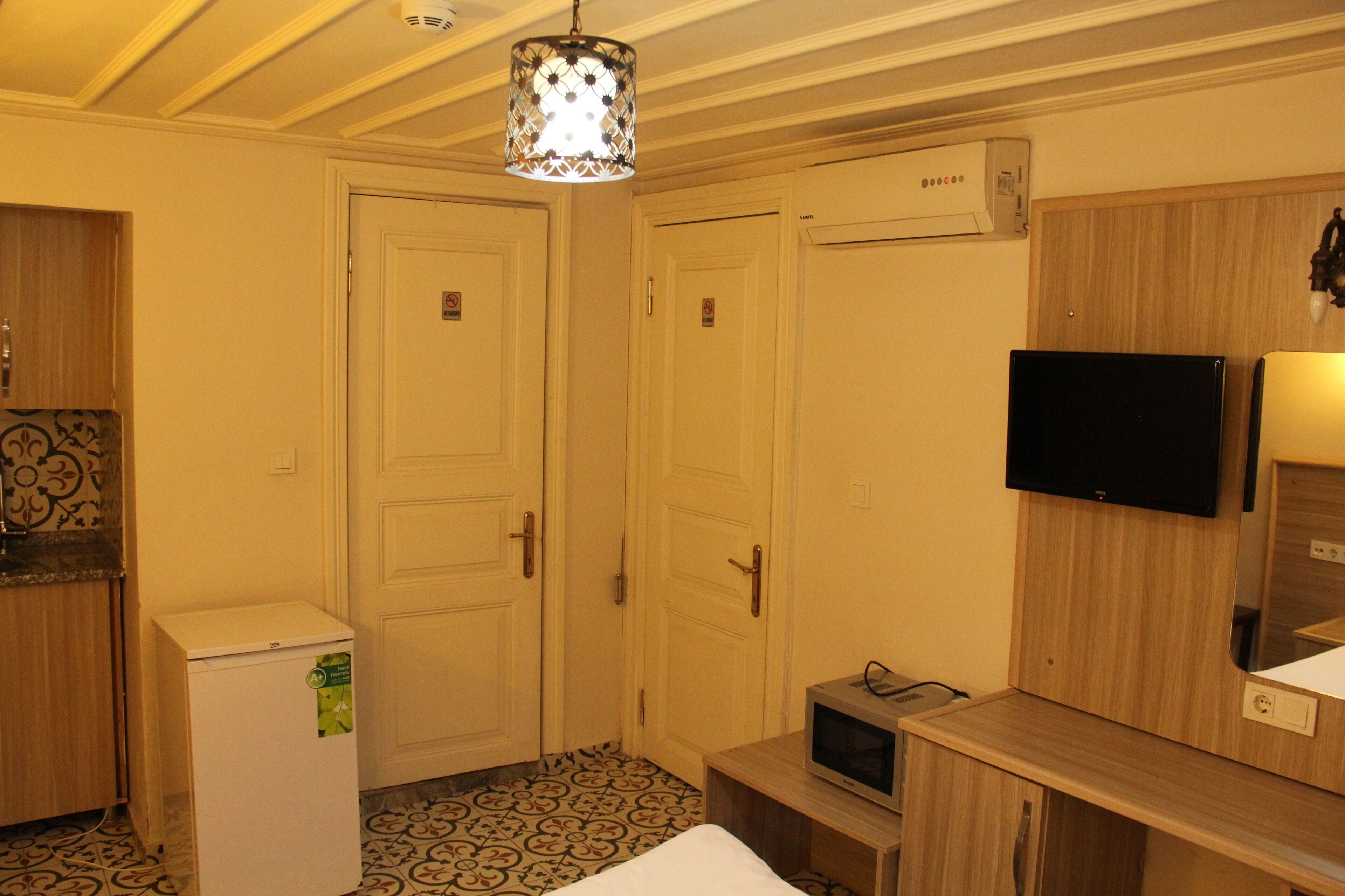 Habitació d'hotel amb un llit, nevera petita, televisió i microones.