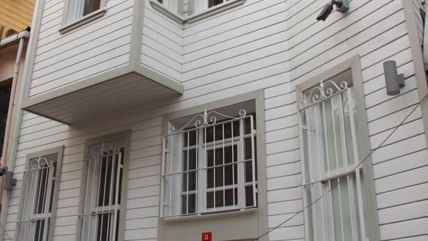 A corner building with white siding, multiple windows, and a small balcony. - Jasmine Apartment (Istanbul)