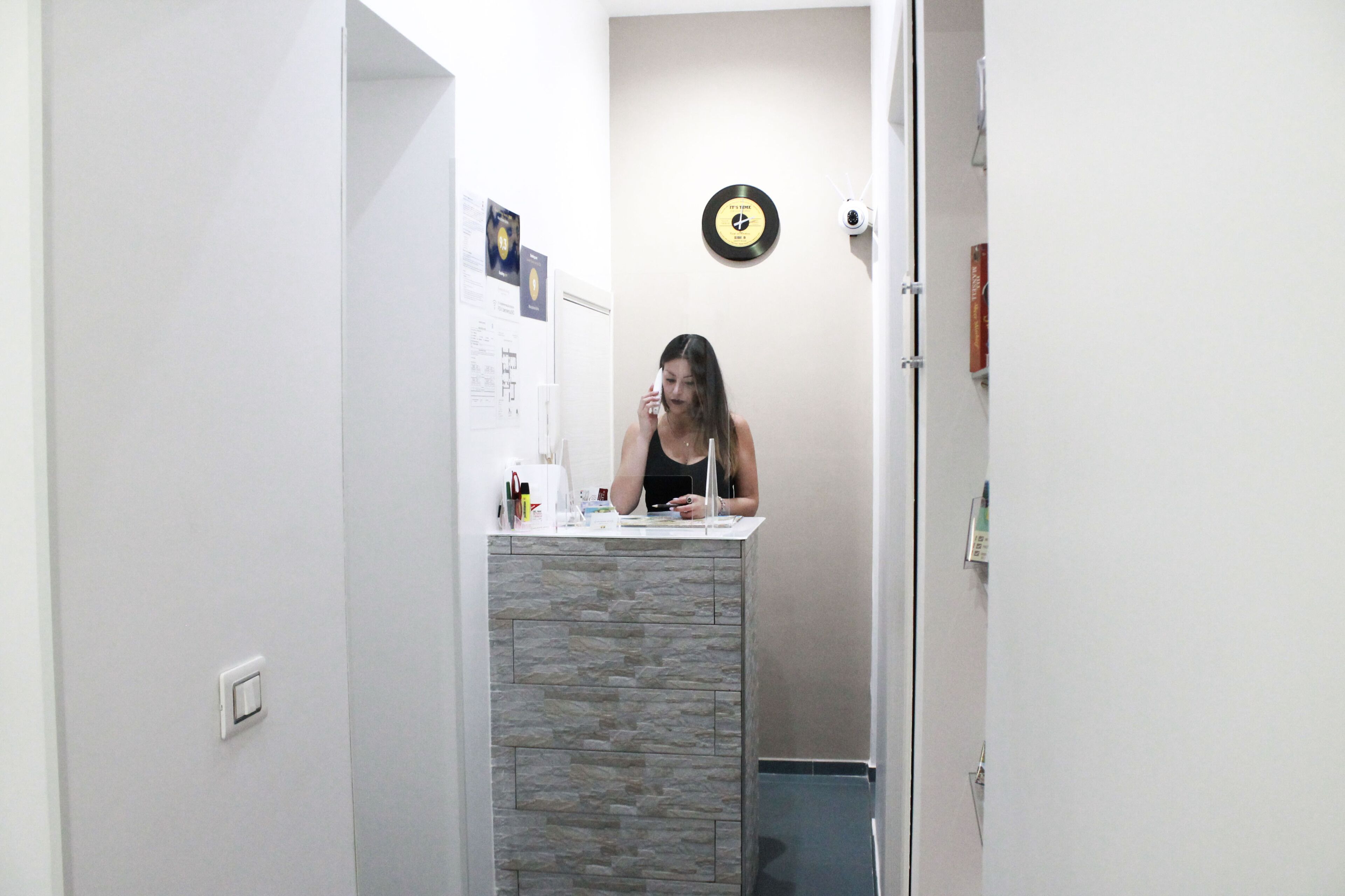 Un baño con encimera de piedra, un reloj en la pared y una puerta que da a otra habitación.