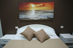 A bed with two beige pillows, a white headboard, and a painting of a sunset over the ocean on the wall behind it. - Mascalzone Latino Luxury Rooms (Naples)