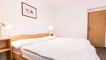 Een net opgemaakt bed met witte lakens en twee bedlampjes.