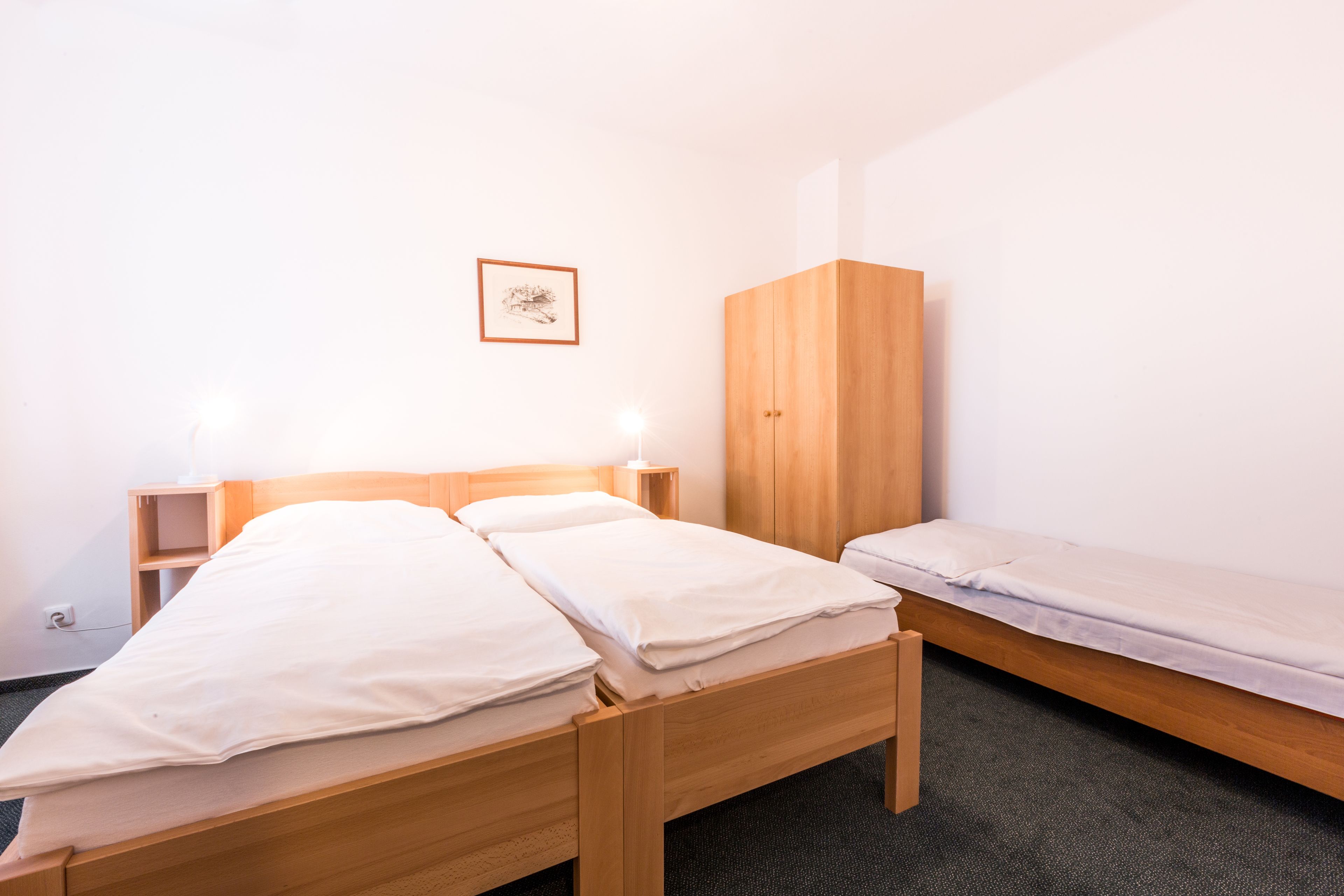 Una habitación con una cama de madera, un armario de madera y una mesita de noche con una lámpara.