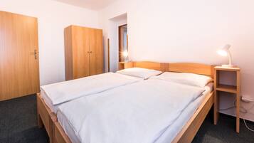 A double bed with a wooden headboard, a bedside table with a lamp, and a wardrobe.