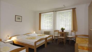 A room with two wooden beds, a small table with chairs, and a radiator.