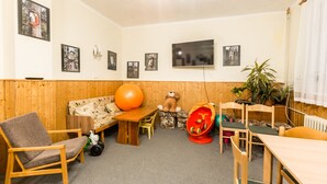 Una habitación acogedora con suelo de madera, un sofá, una mesa, una silla, un televisor y cuadros enmarcados en la pared.