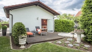 A house with a deck, two lounge chairs, a potted plant, and a garden with a stone path. - Hotel Bei Den Tongruben (Neuberg)