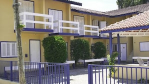Un edificio de dos pisos con balcones, un patio cubierto y un patio de grava.