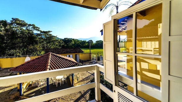 Un balcón con vista a una casa y follaje circundante.