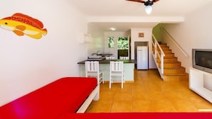 Un espacio habitable compacto con kitchenette, zona de comedor, escalera y televisor.