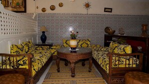 Um quarto com paredes estampadas, uma mesa redonda de madeira e dois sofás com almofadas combinando.