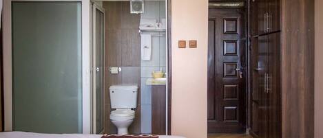 Una habitación de hotel con cama, baño con inodoro y lavabo, y un armario.