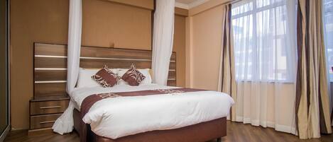 A bedroom with a large bed, wooden headboard, and a nightstand.