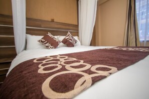 A neatly made bed with a brown and white patterned bedspread, white pillows, and a wooden headboard.