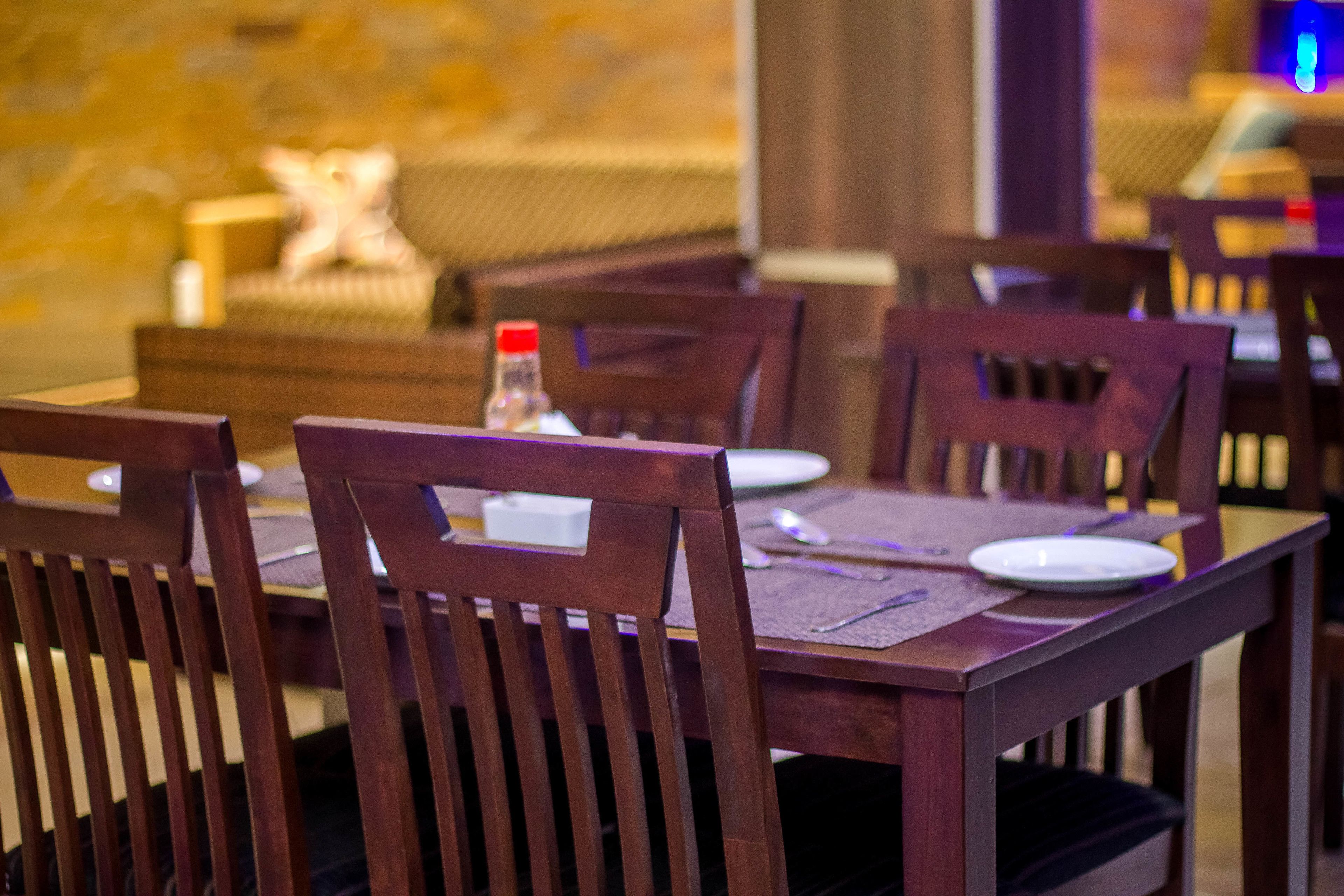 A dining area with wooden tables and chairs, a bottle of water, and a plate on the table.