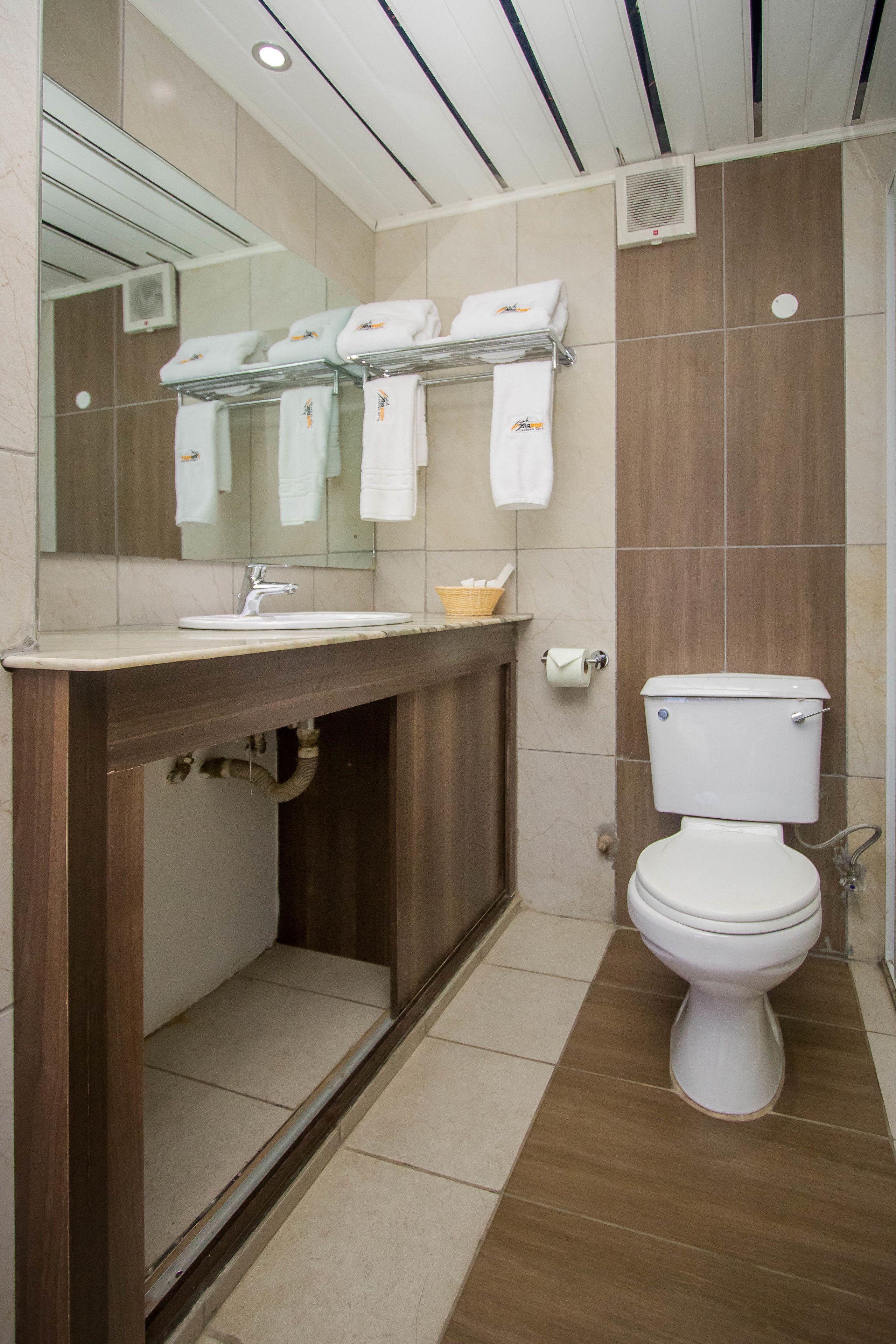 A modern bathroom with a wooden vanity, a white sink, a mirror, and a toilet.