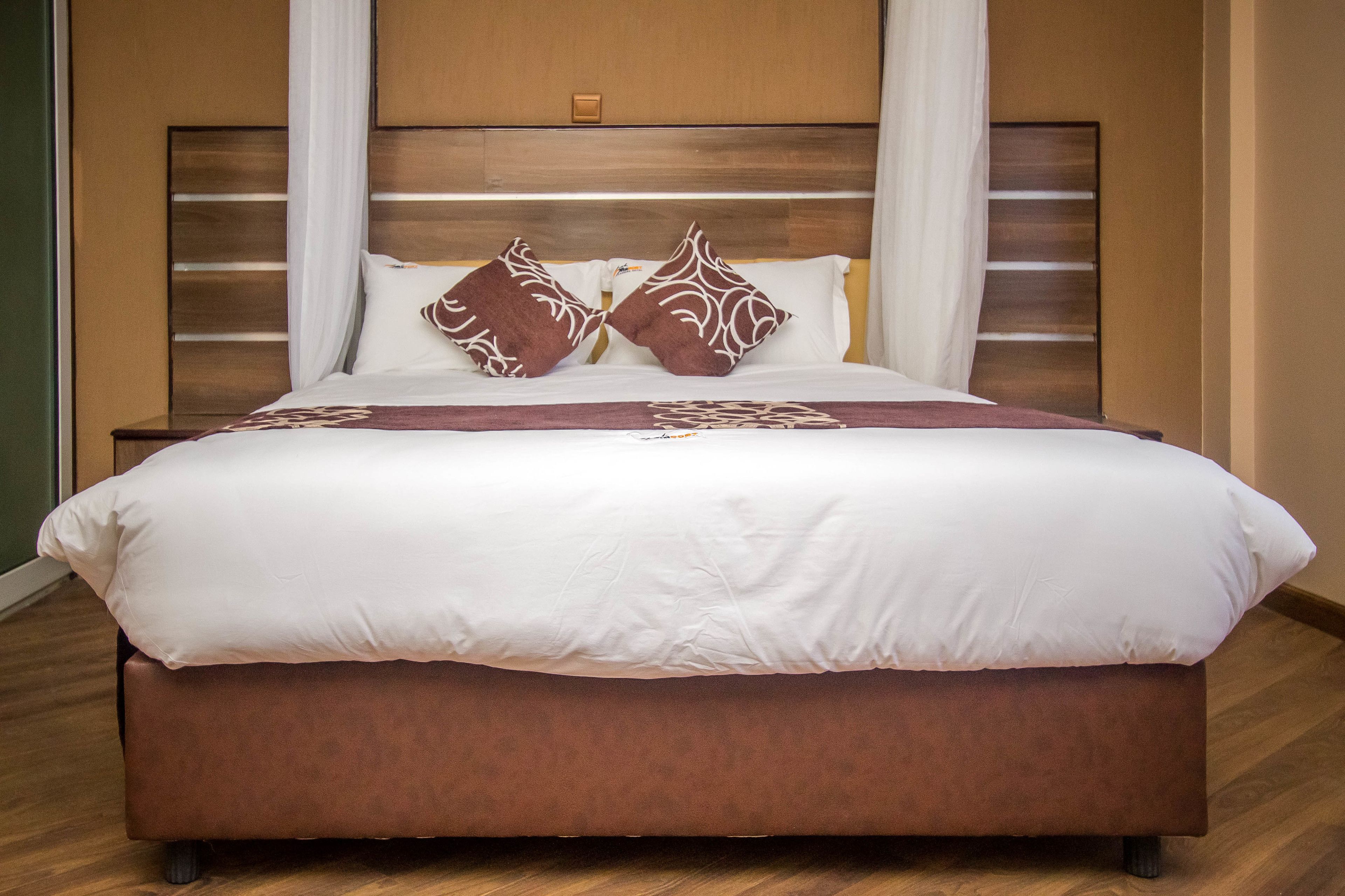 A large bed with a wooden headboard, white bedding, and decorative pillows.