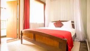 A bed with a wooden frame, white bedding, and a red blanket. - Desmond Tutu Conference Centre (Nairobi)