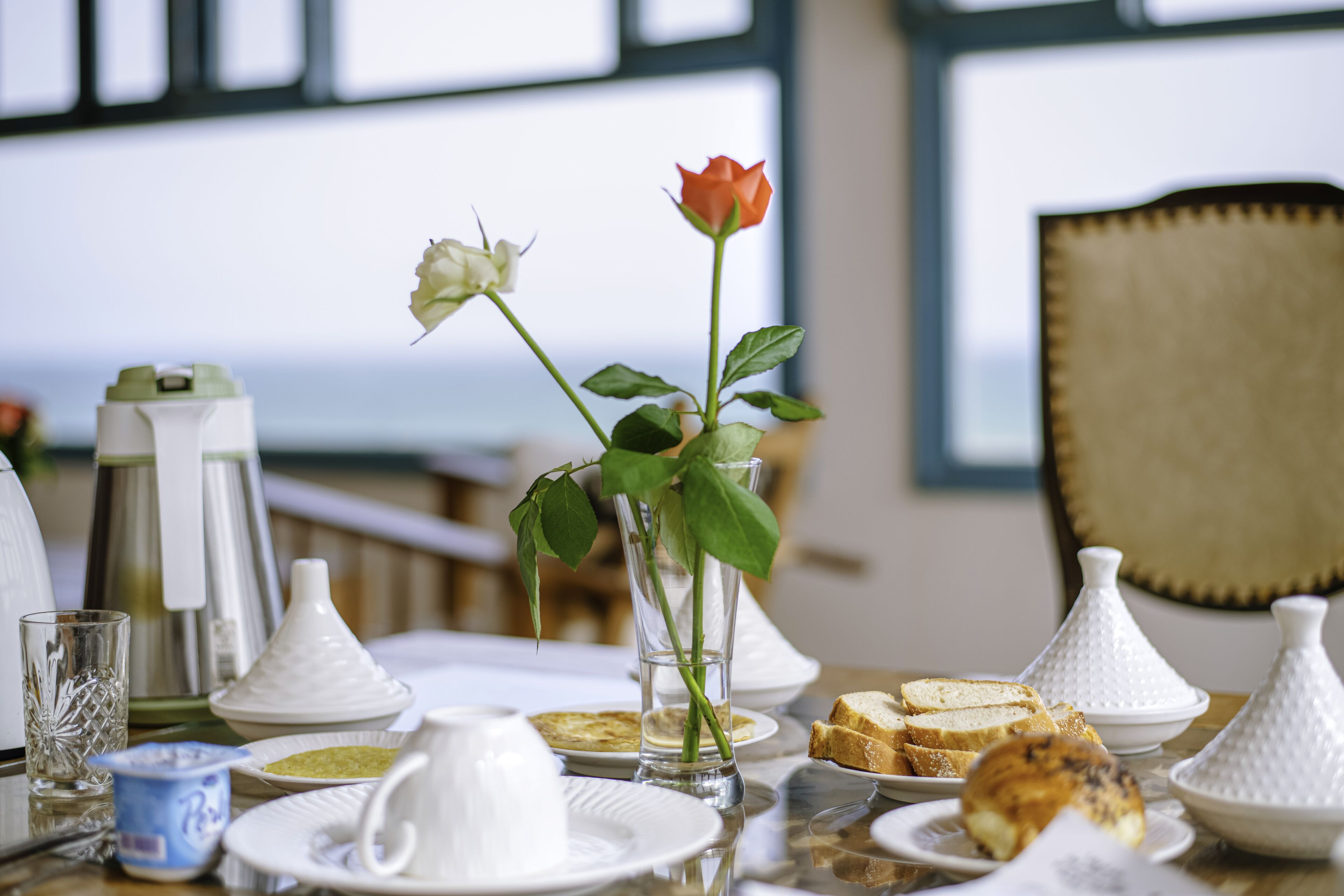 A dining table with plates, glasses, and a vase with flowers.