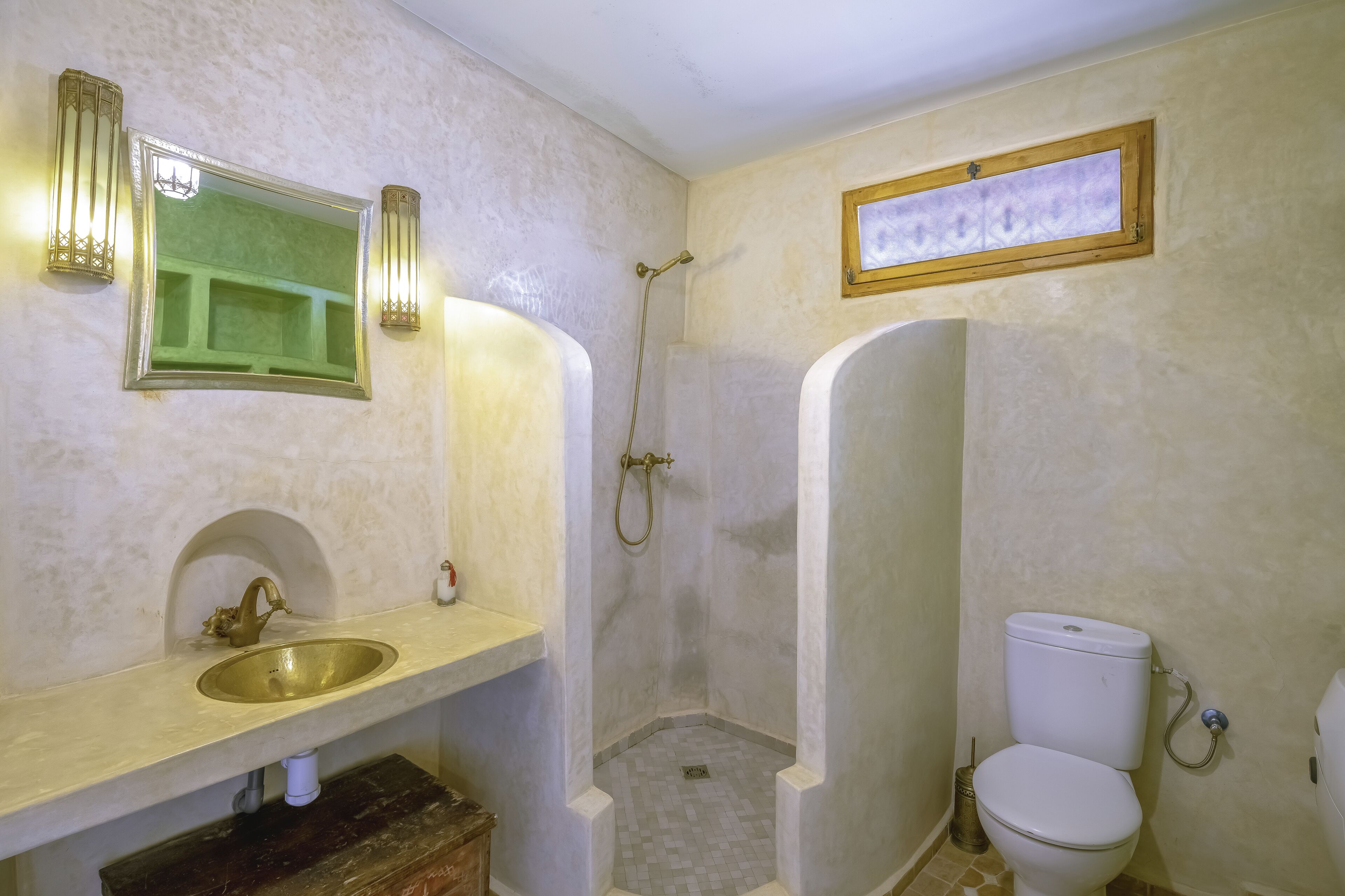 A bathroom with a sink, mirror, shower, and toilet.