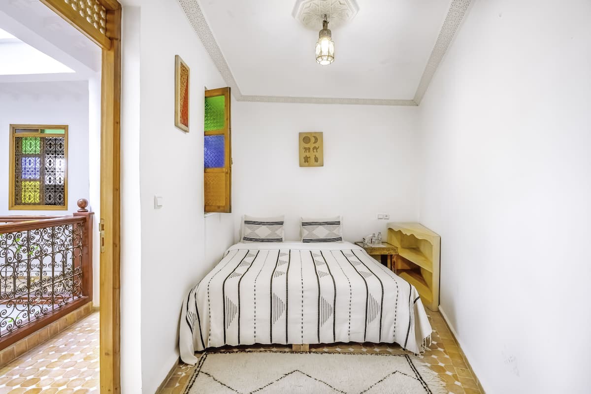 Un dormitorio con cama, mesita de noche, repisa en la pared y un adorno mural.