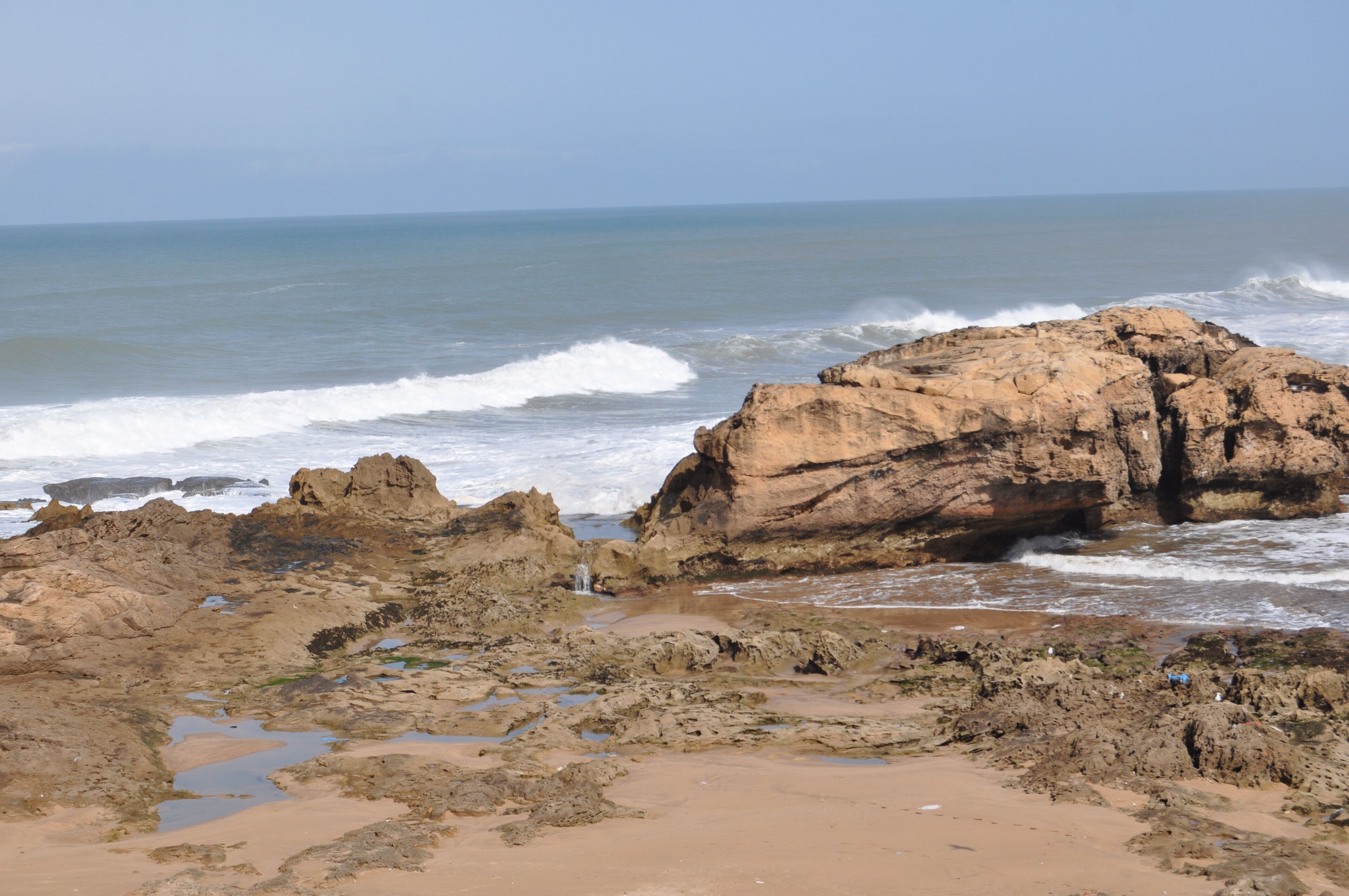 A rocky coastline with waves crashing against large boulders.