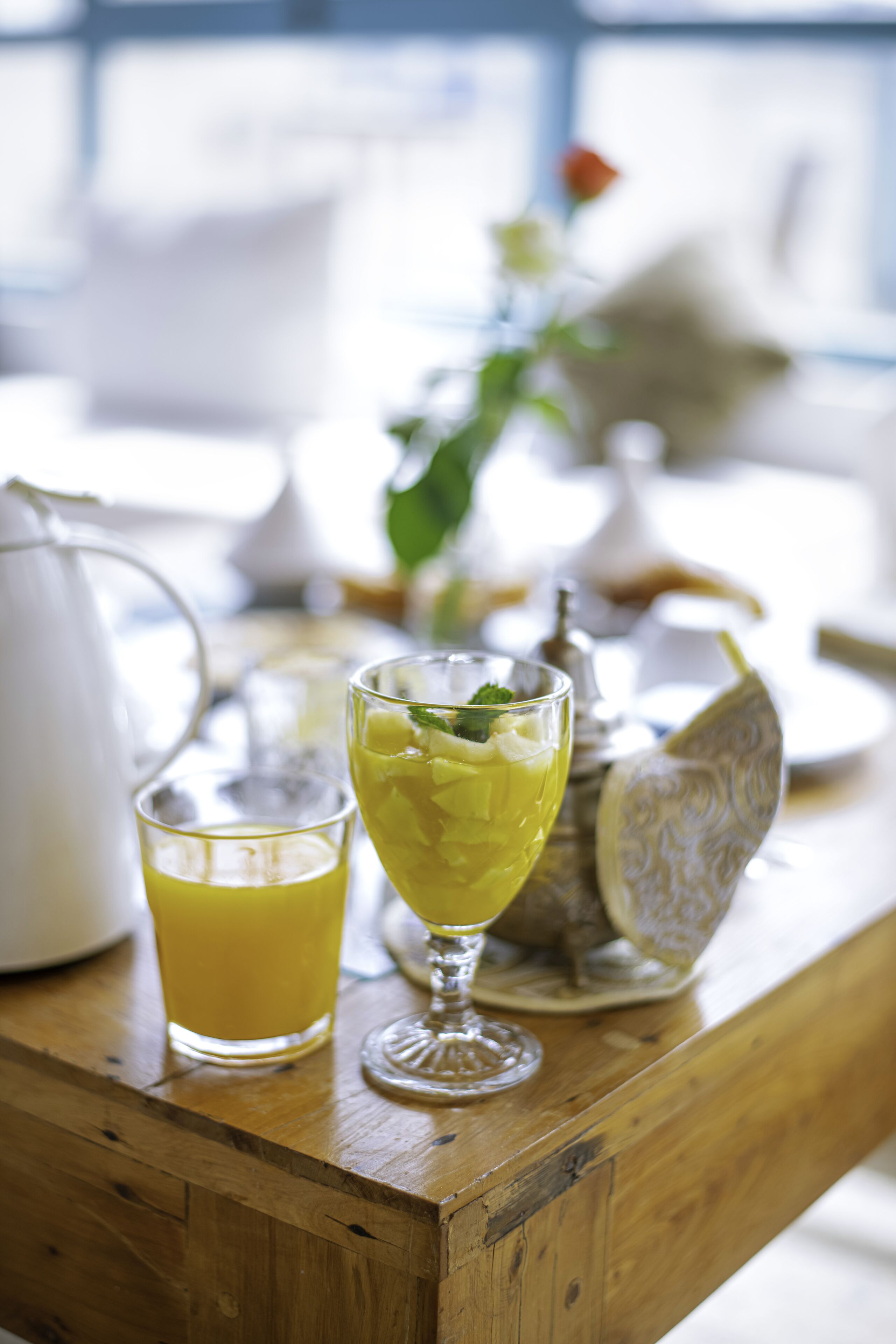 Een houten tafel met een glas geel drinken, een karaf en een decoratief bord.