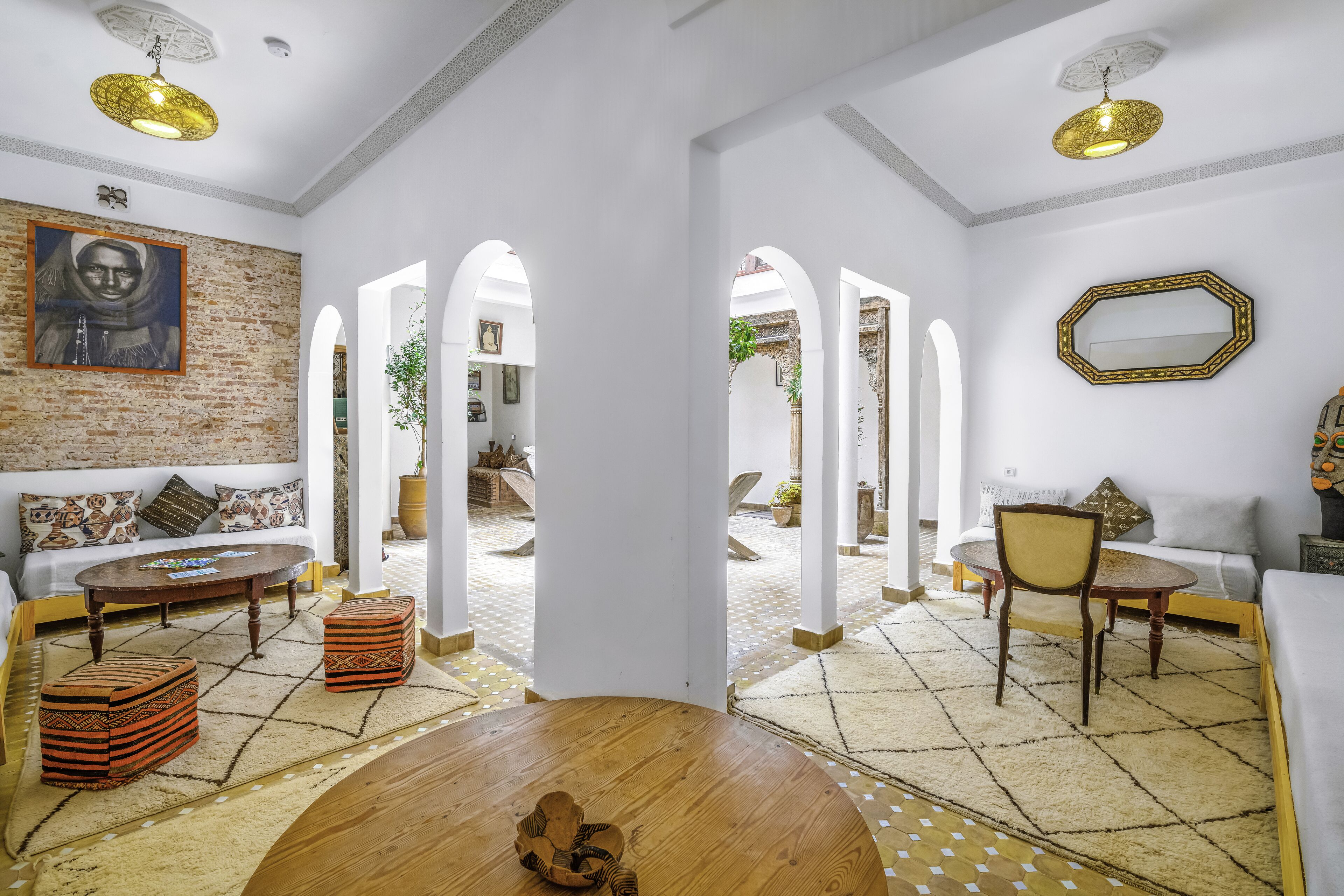 A spacious living area with a brick accent wall, a round wooden coffee table, and a sofa with patterned cushions.