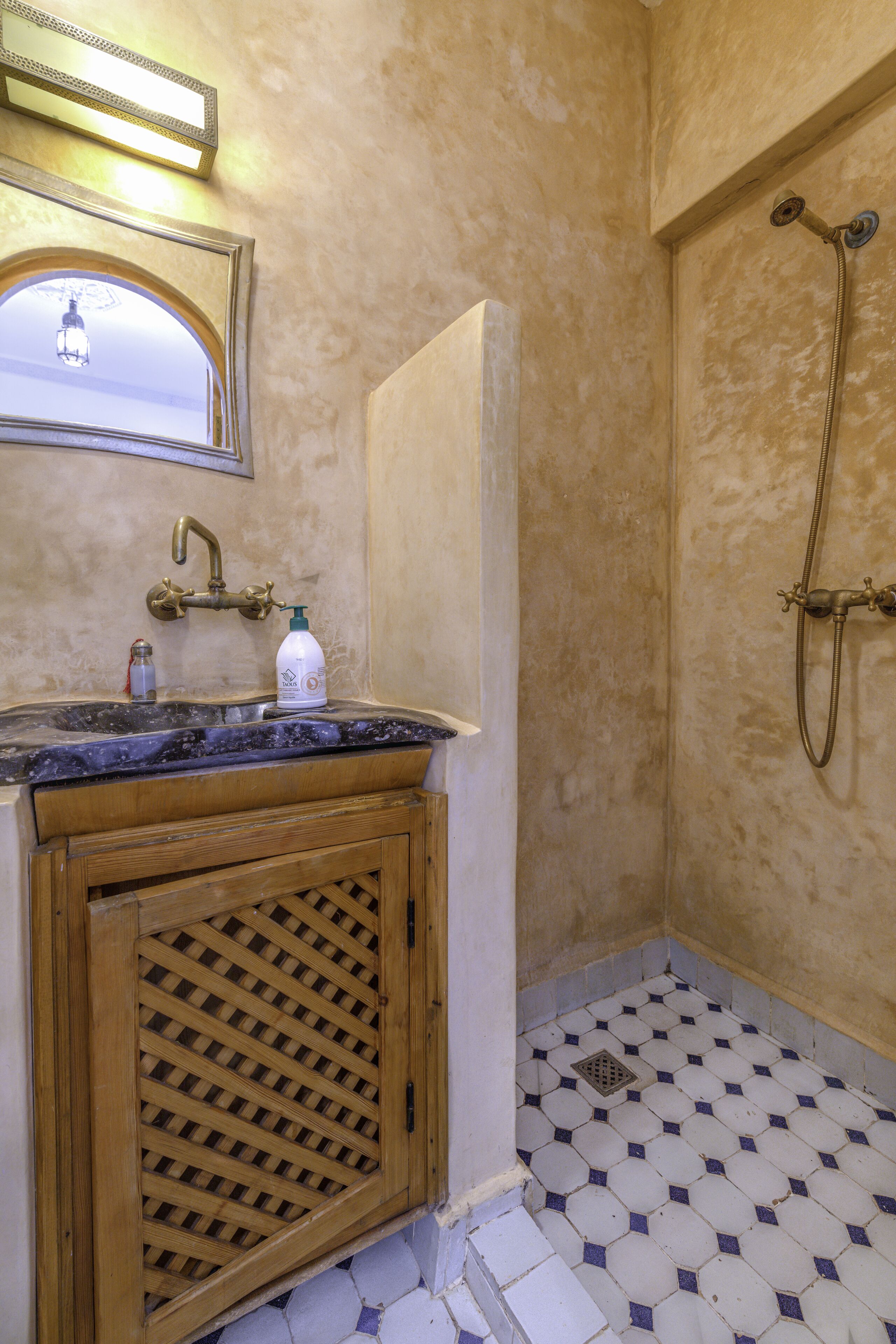 Un baño con lavabo, espejo, ducha y suelo de baldosas.