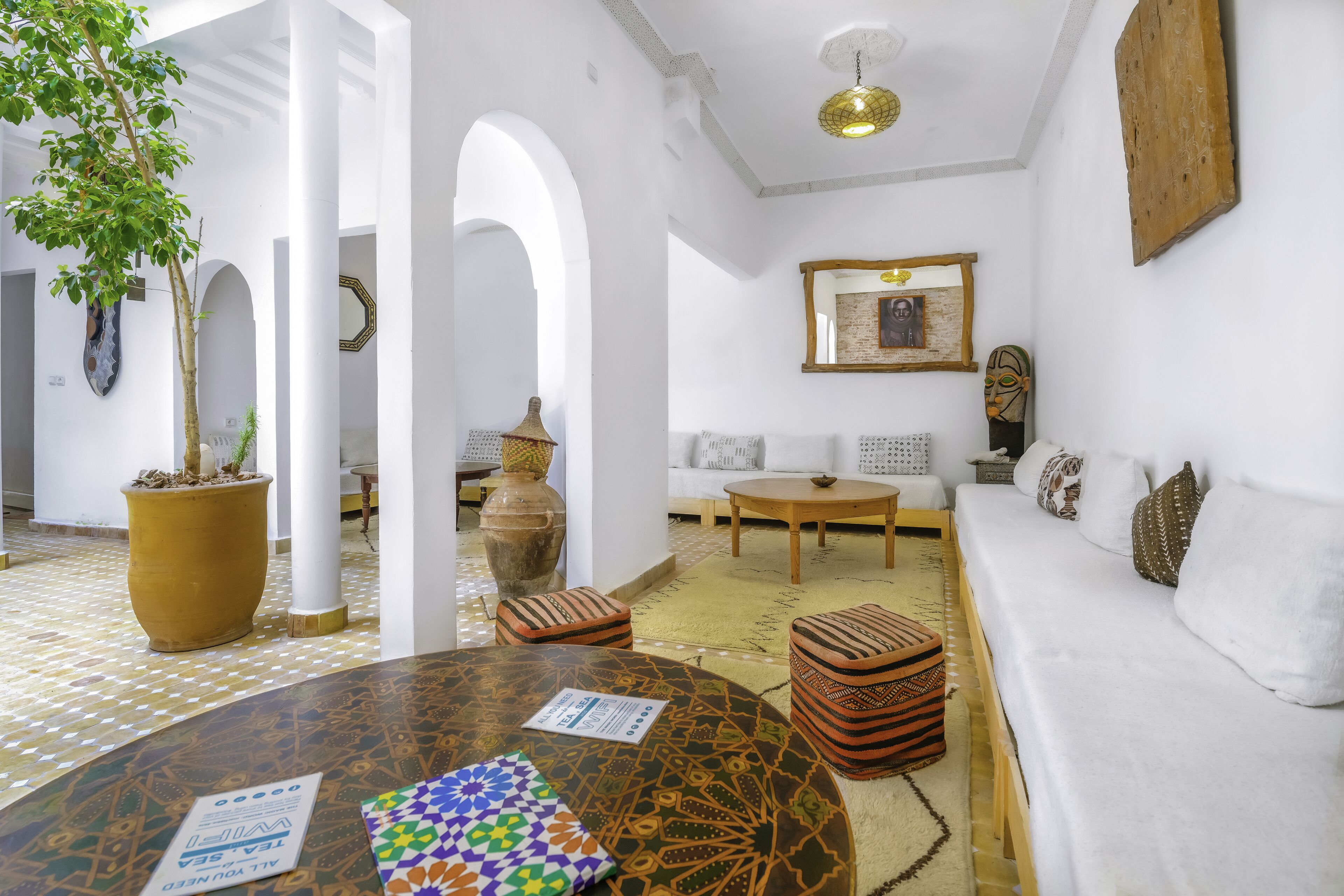 A spacious room with a white sofa, a round table, and a potted plant.